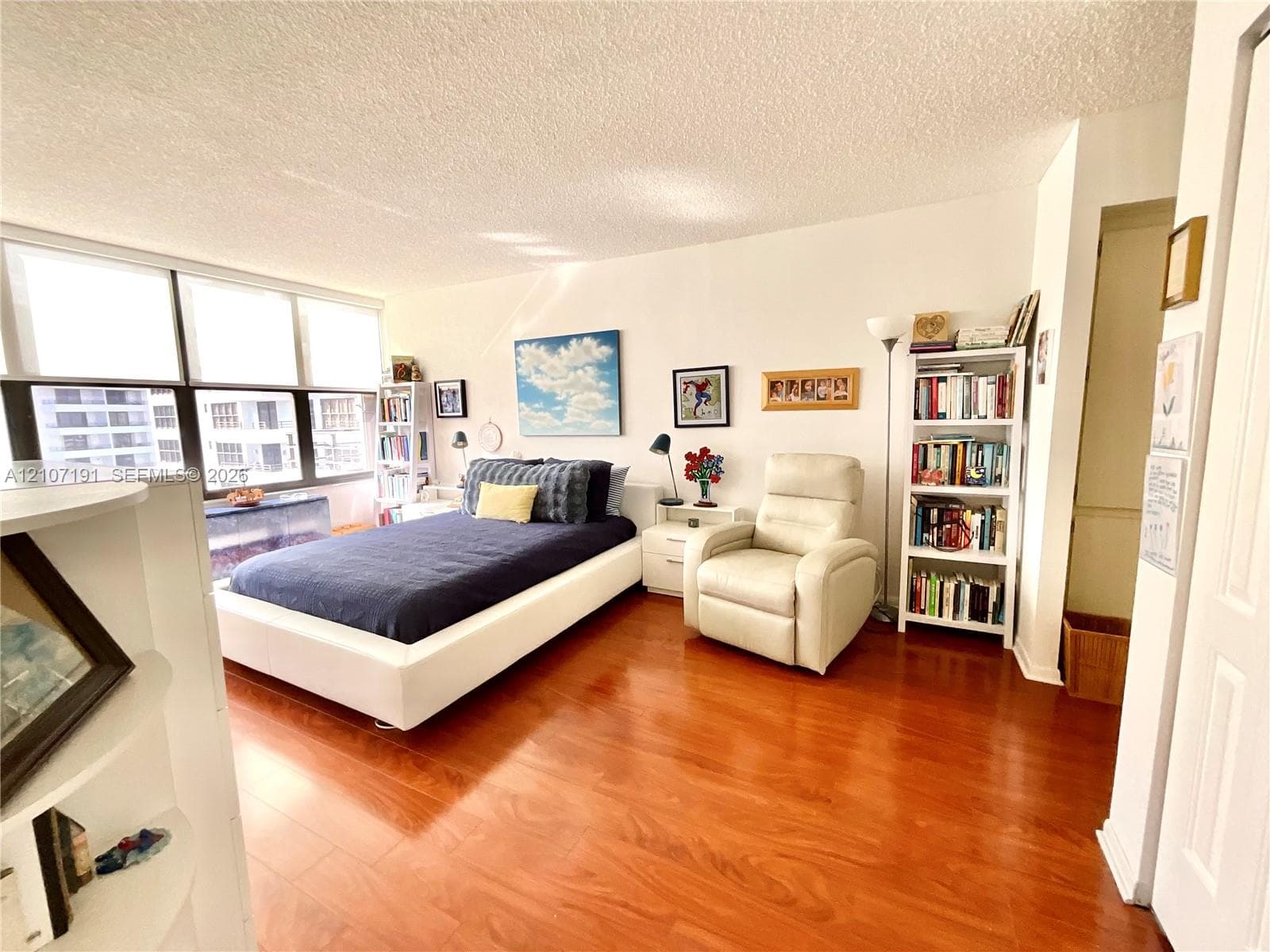 Living space featuring wood-finish flooring, floor-to-ceiling windows, and a textured ceiling