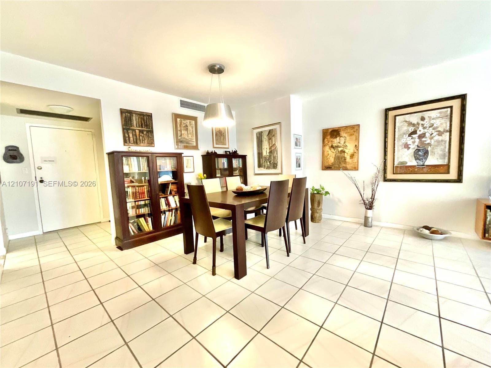Open-concept area featuring neutral oversized tile flooring and a polished metal pendant light fixture