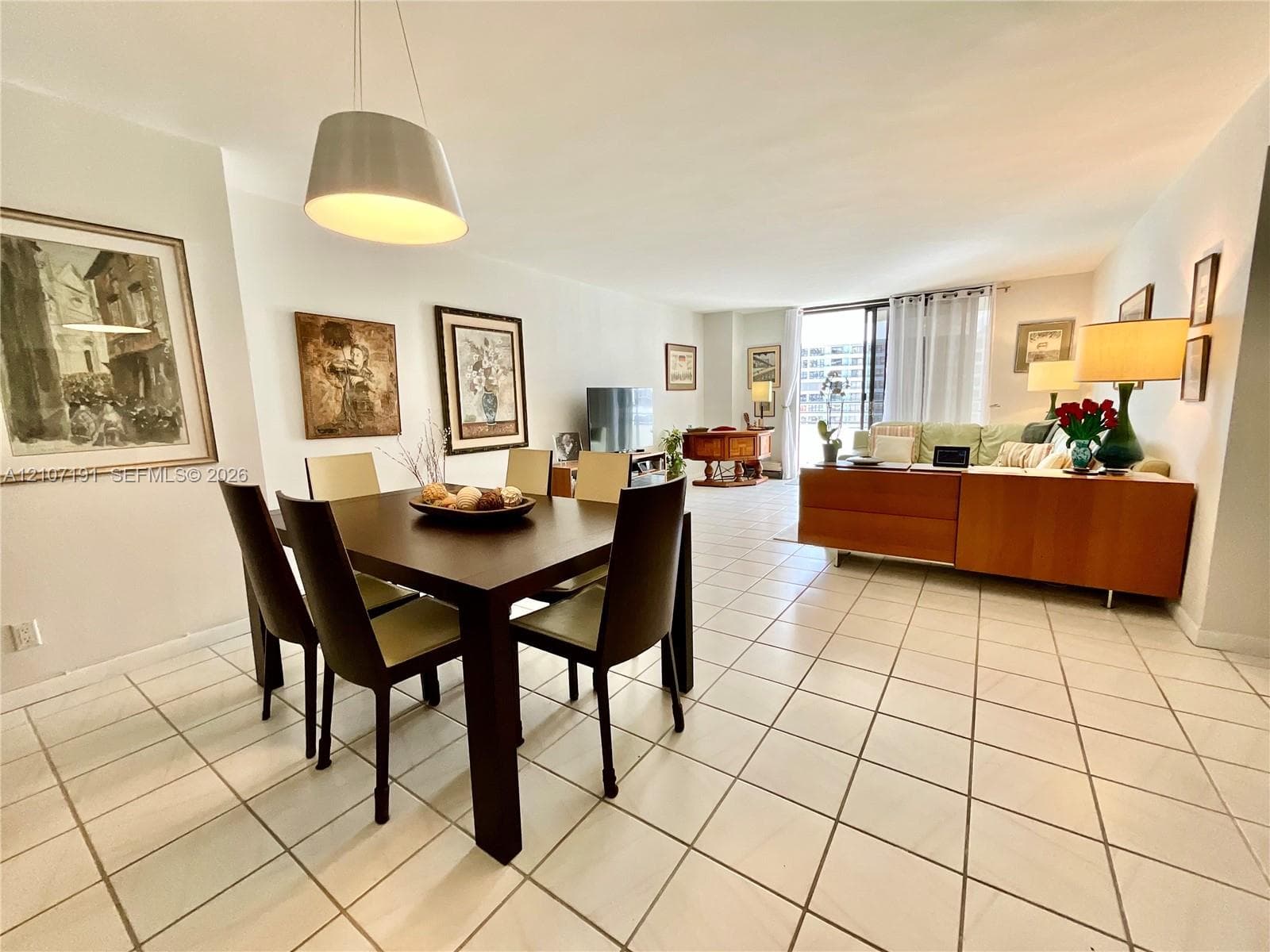 Open-concept interior space featuring ceramic tile flooring, neutral wall paint, and a modern pendant light fixture