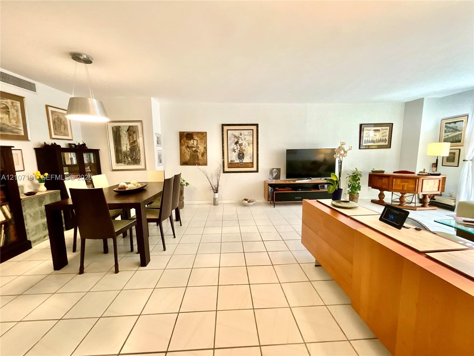 Open-concept interior featuring large-format ceramic tile flooring, neutral wall finishes, and a modern drum-style pendant light fixture
