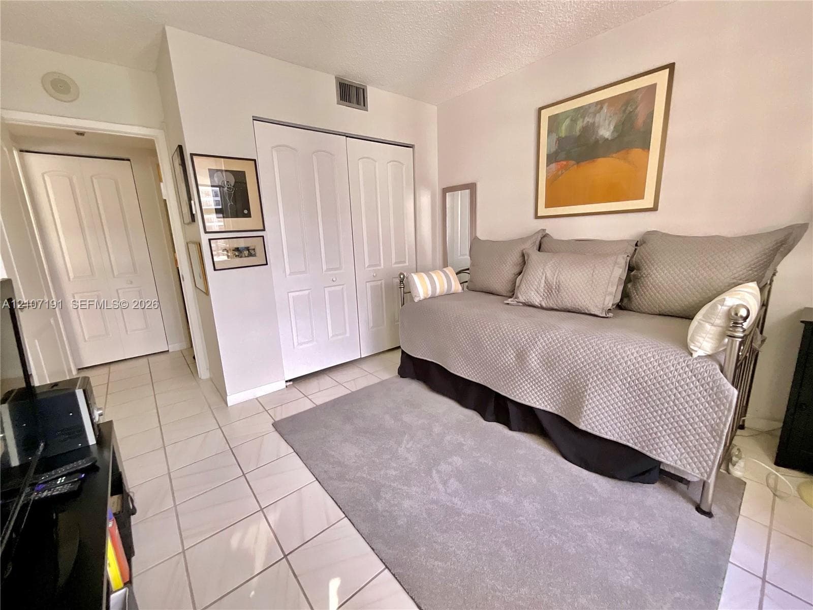 Neutral ceramic tile flooring and white paneled closet doors