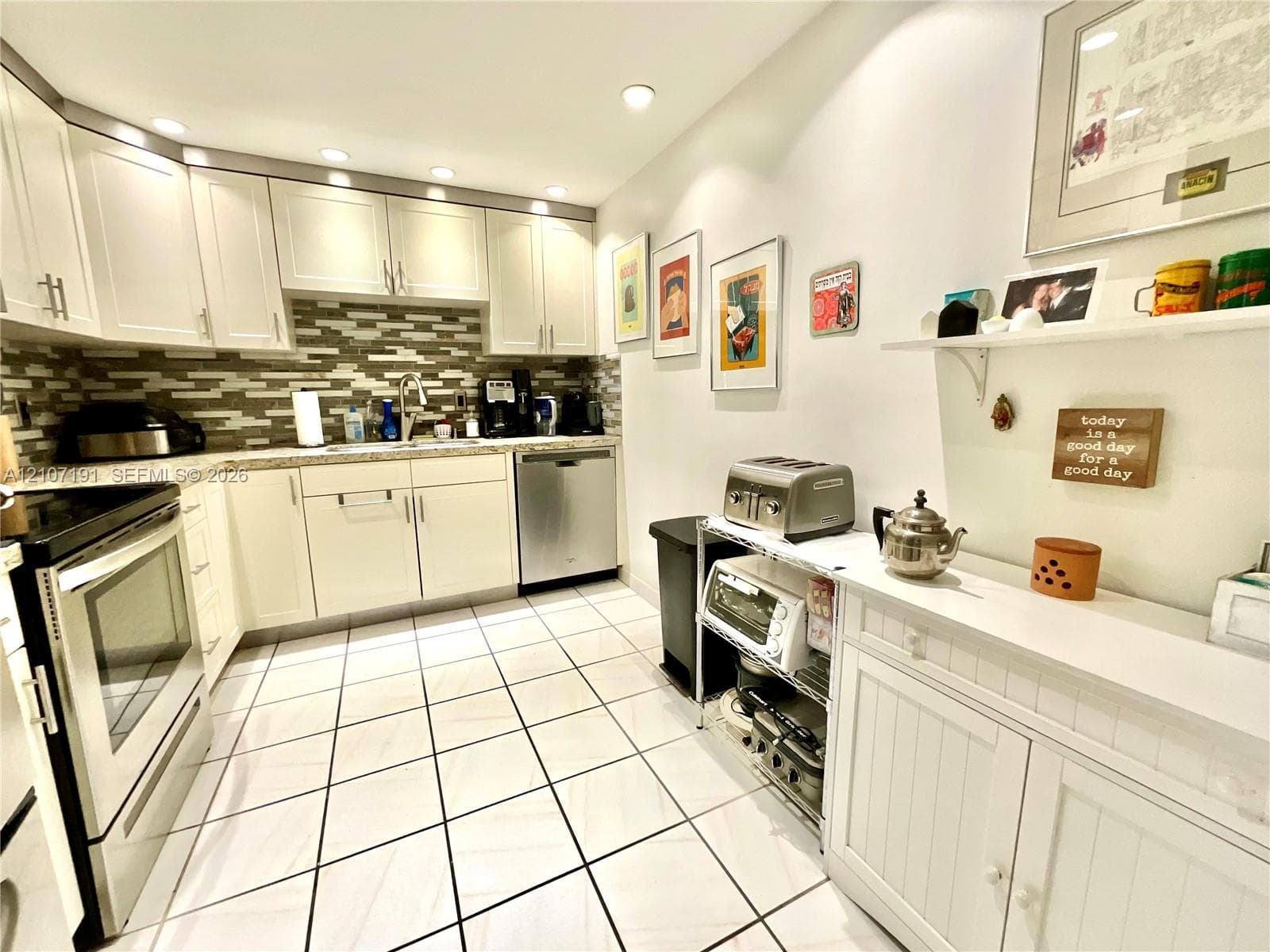 Kitchen featuring white cabinetry, stone-finish countertops, tile backsplash, stainless steel dishwasher, and ceramic tile flooring
