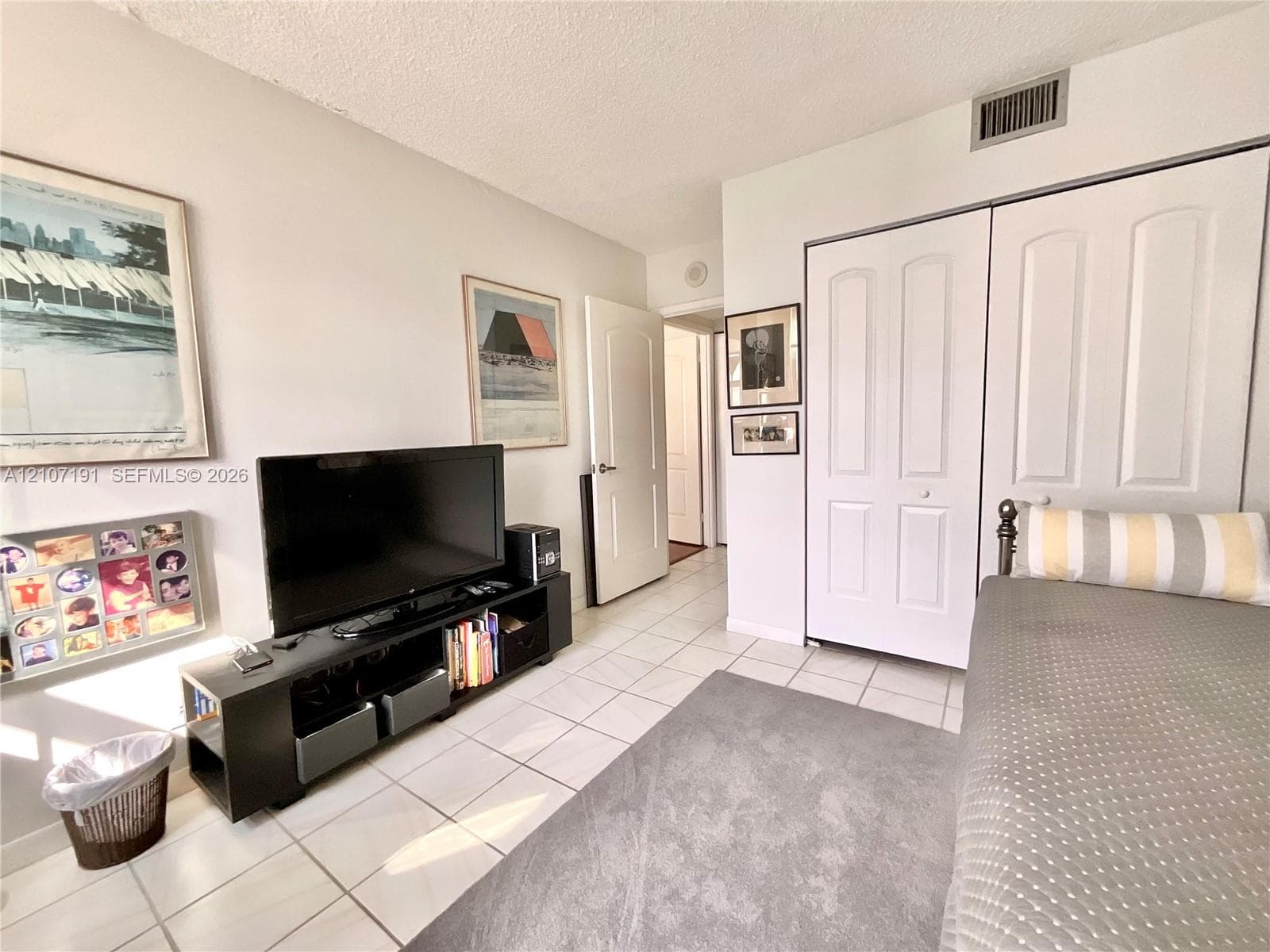 Interior room featuring large-format ceramic tile flooring, double-door closet with raised-panel doors, and solid-core interior doors with satin nickel hardware