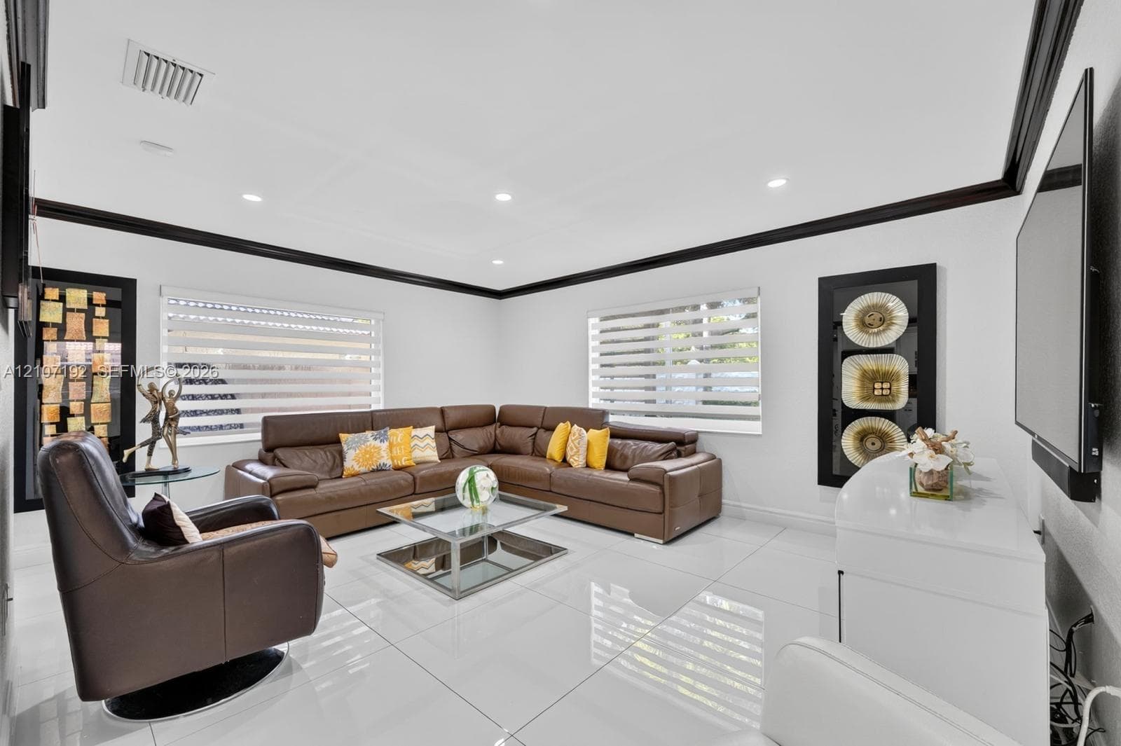 Living area featuring large-format tile flooring, high-contrast black crown molding, recessed lighting, and dual-layered horizontal window blinds