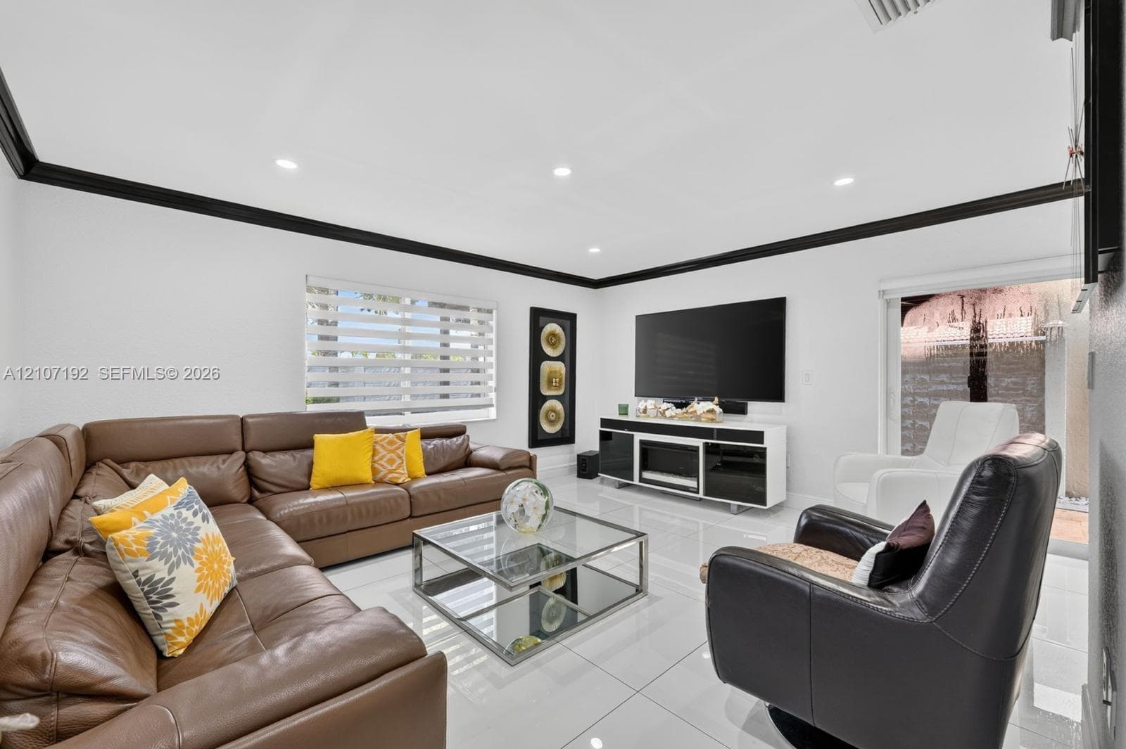 Living space featuring high-gloss tile flooring, crown molding, recessed lighting, and dual-shade window treatments