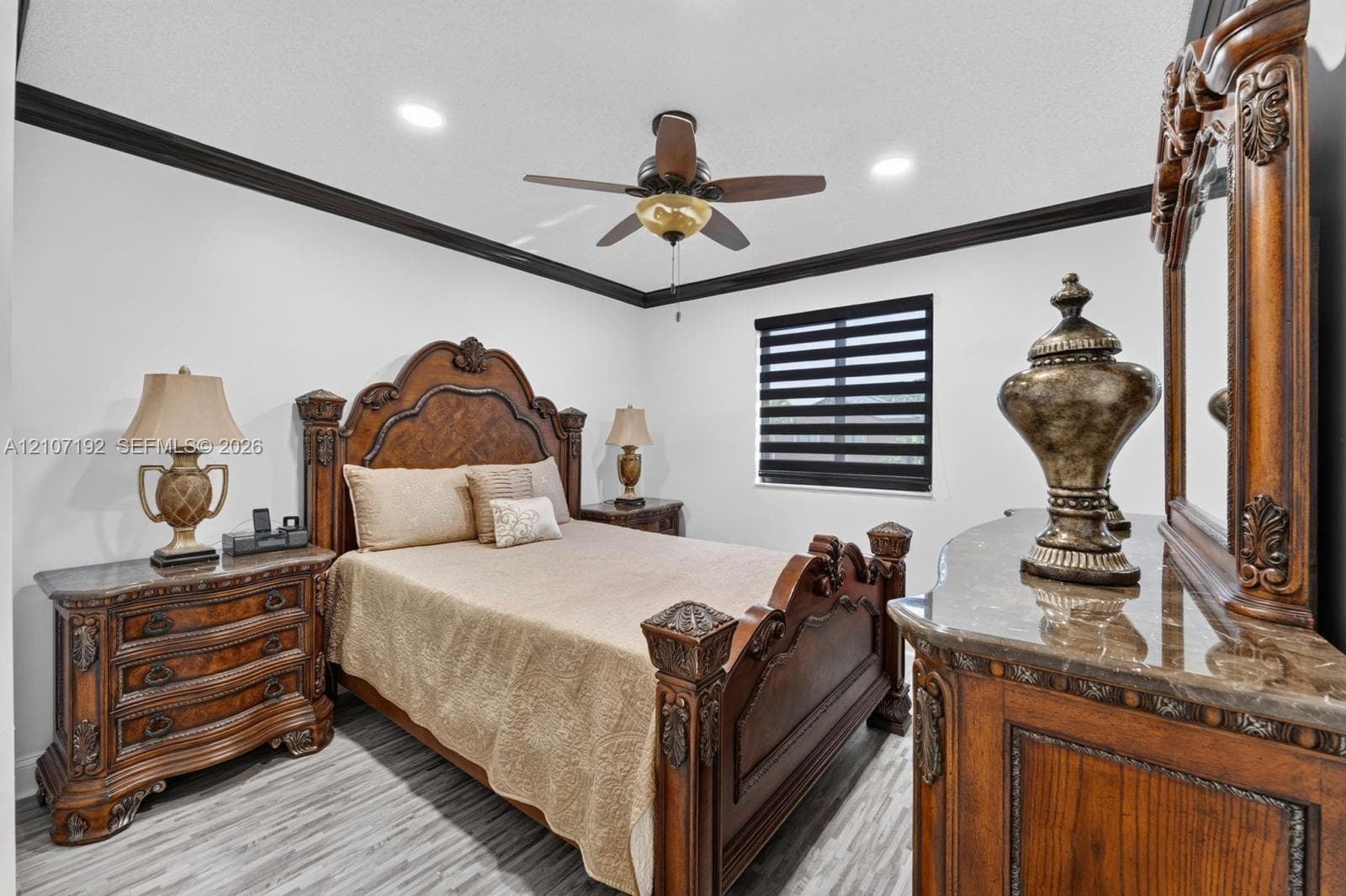 Bedroom featuring wood-finish flooring, dark crown molding, a central ceiling fan with integrated lighting, recessed lighting, and a window with horizontal blackout shades