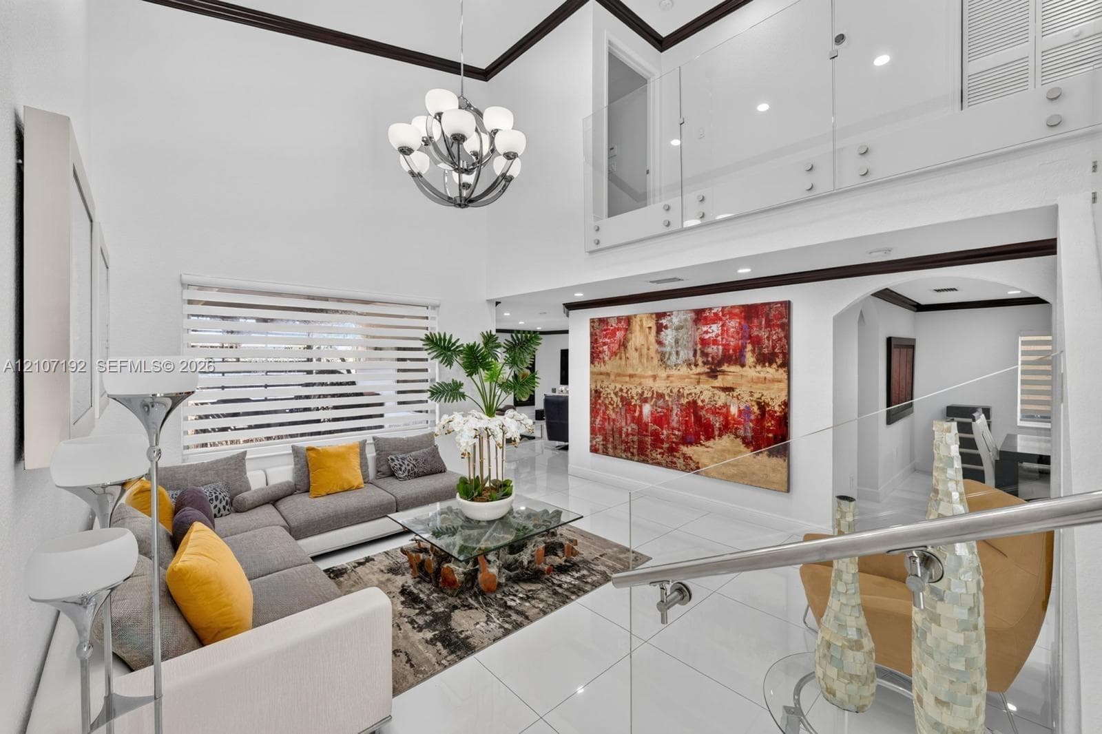 Double-height ceiling, glass-panel staircase railing, multi-tiered chandelier, large-format tile flooring, and recessed lighting