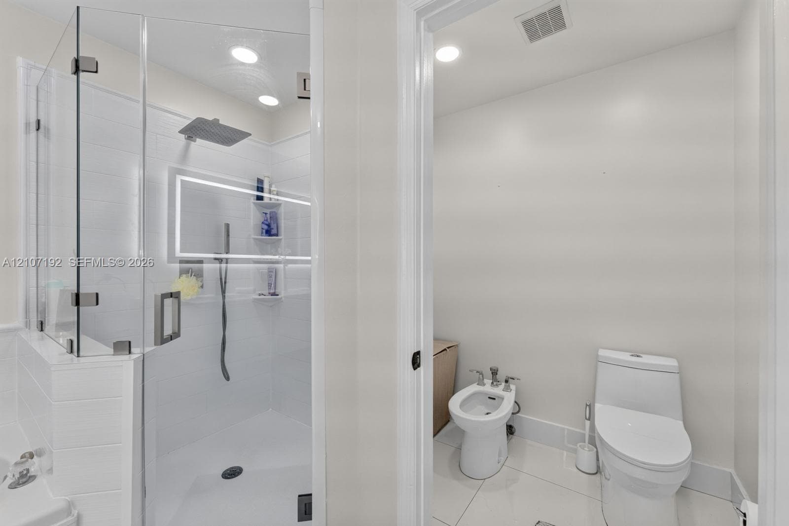 Glass-enclosed shower with rainfall showerhead, integrated LED lighting, built-in shelving, bidet, and elongated commode