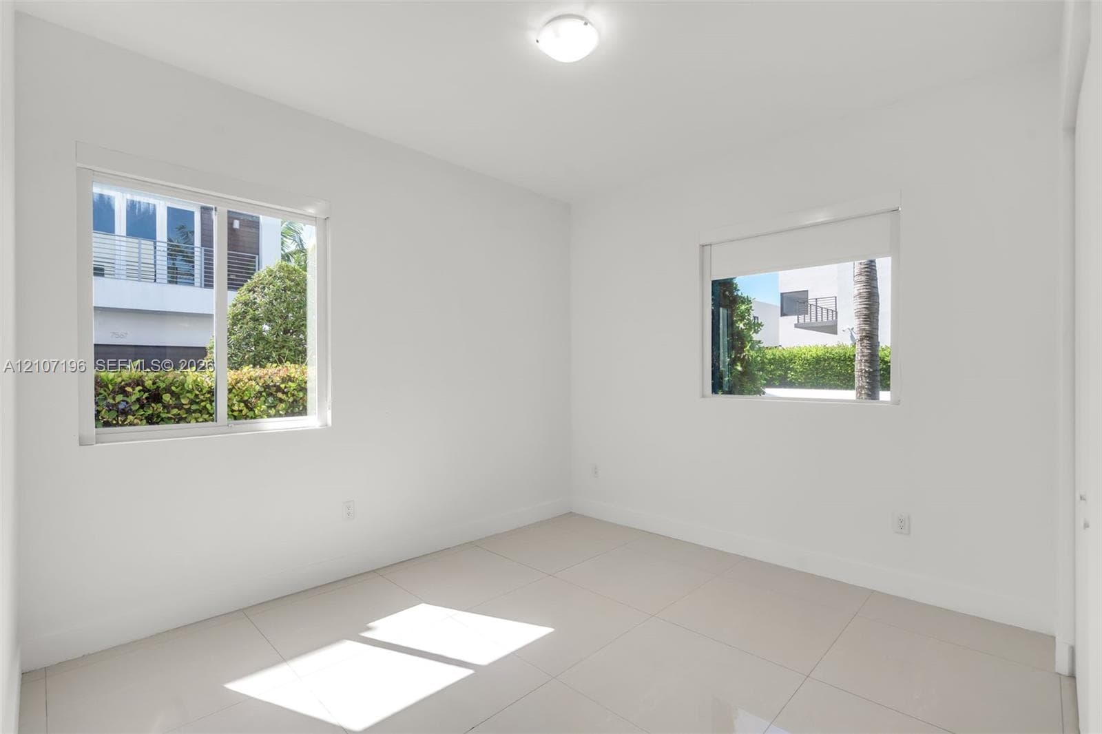 Neutral-toned tile flooring, flush-mount ceiling lighting, and dual windows with built-in roller shades