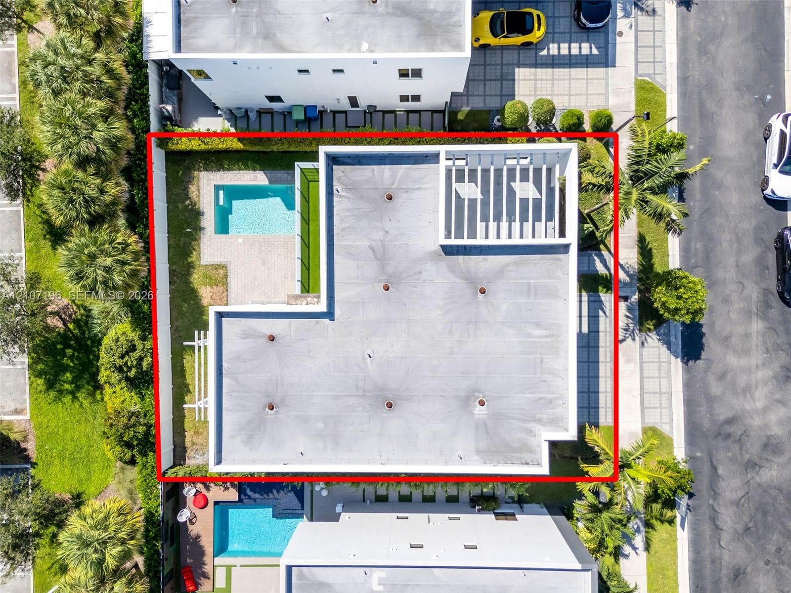 Aerial perspective featuring a private swimming pool, concrete paver patio, structural pergola, and perimeter hedge landscaping