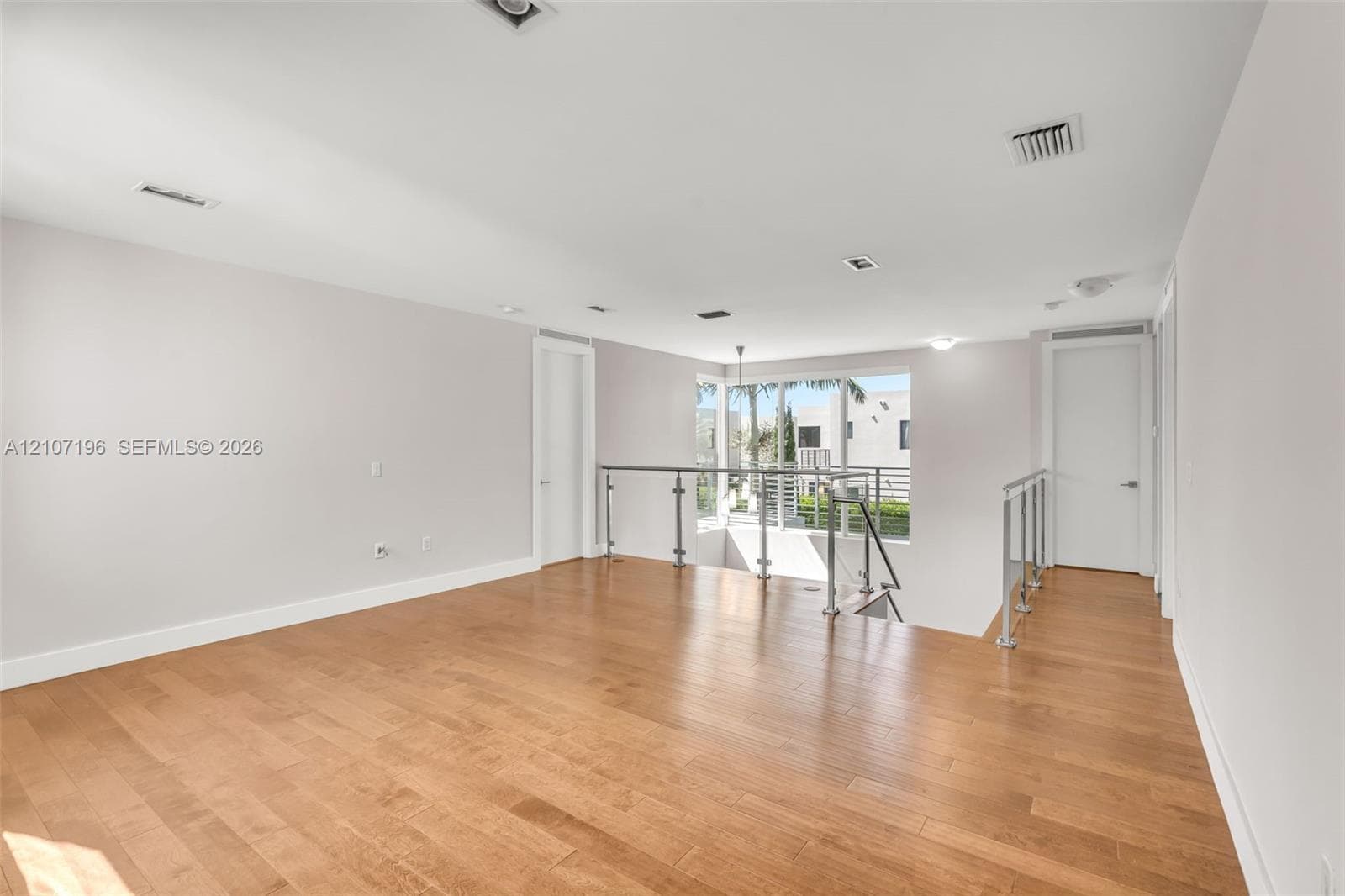 Open-concept interior featuring wood-finish flooring, recessed lighting, and a metal-rail staircase
