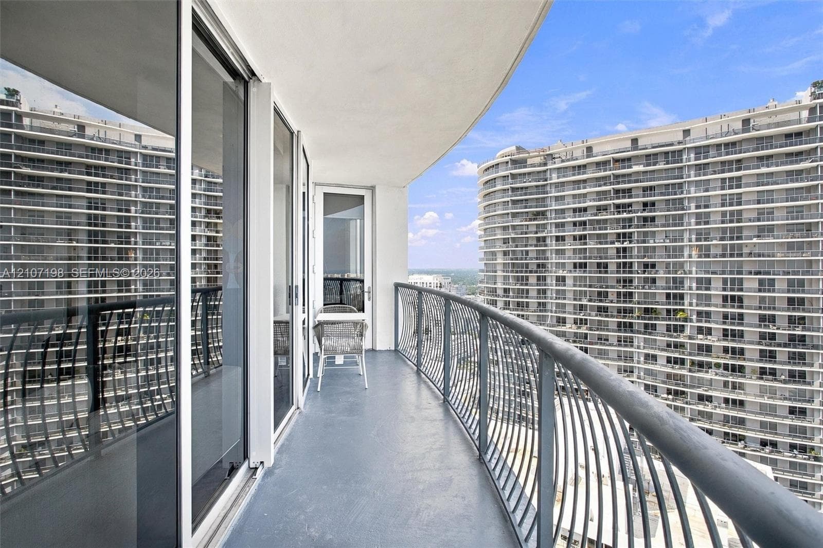 High-rise building featuring a curved architectural design, floor-to-ceiling glass windows, and private balconies overlooking the surrounding bay and coastal waterway