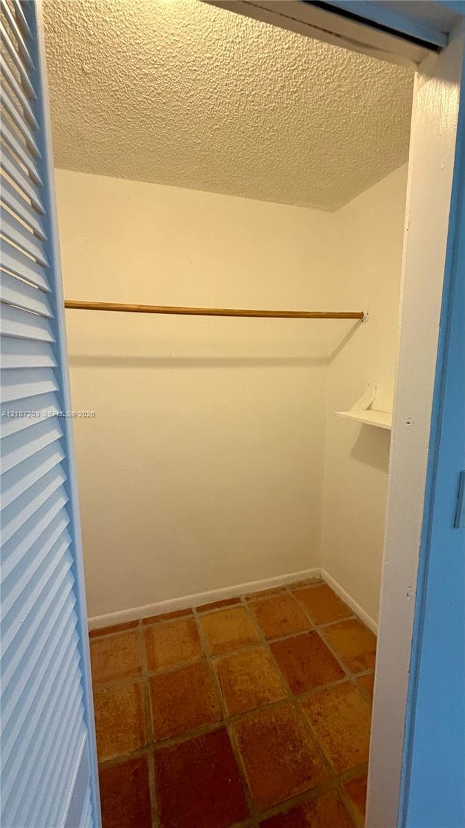 Closet featuring louvered bi-fold doors, clay tile flooring, and built-in rod and shelving