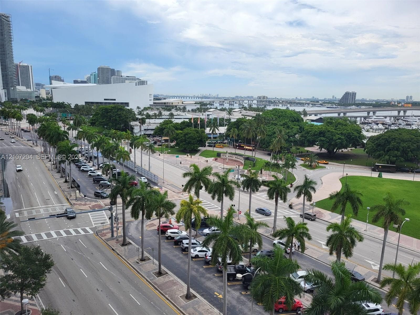 Elevated urban perspective featuring palm-lined thoroughfares, manicured green space, marina proximity, and expansive metropolitan skyline