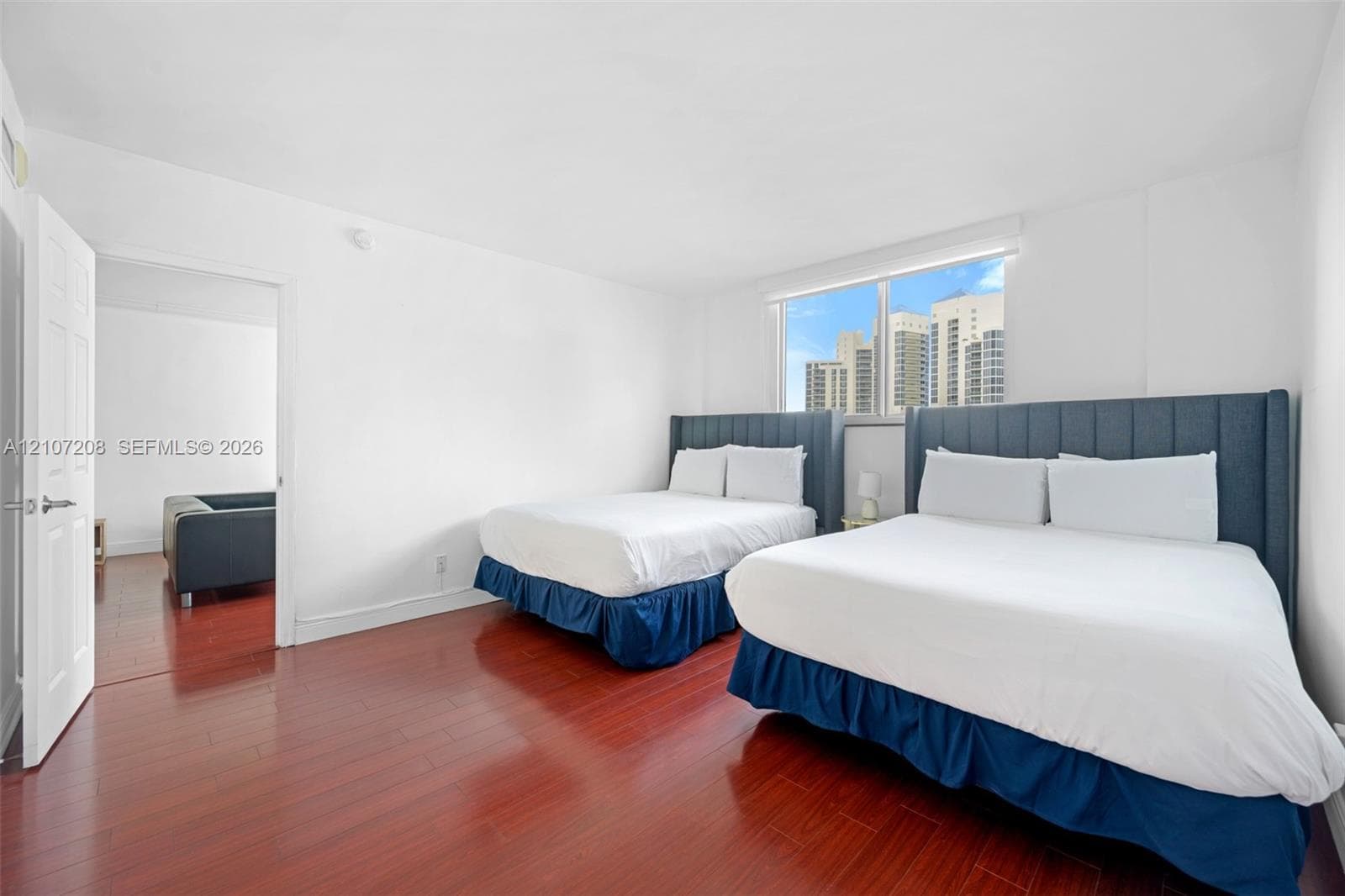 Room featuring wood-finish flooring, a neutral color palette, and a large window with urban scenery