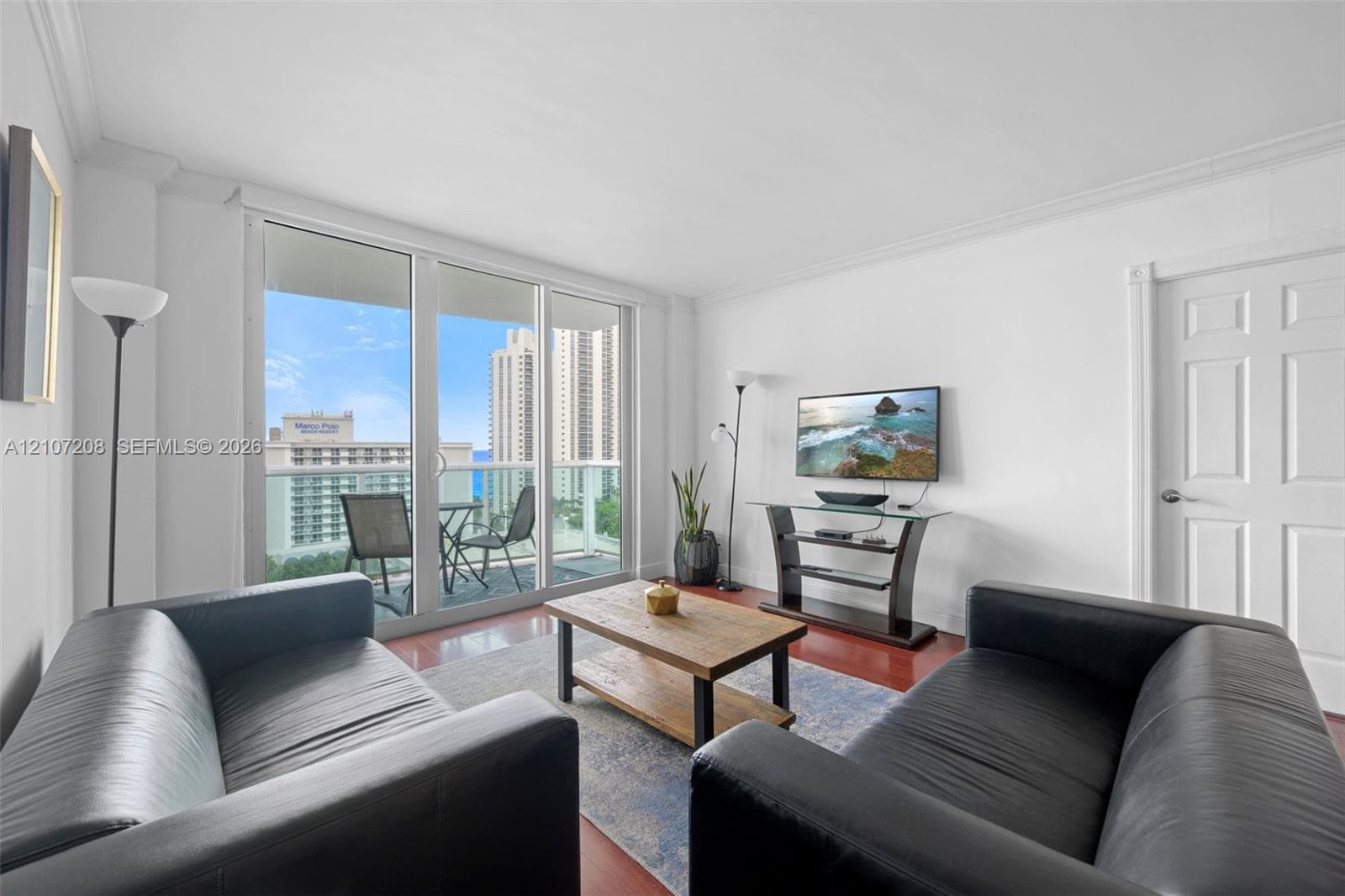 Living space featuring floor-to-ceiling glass sliding doors, private balcony access, and wood-finish flooring