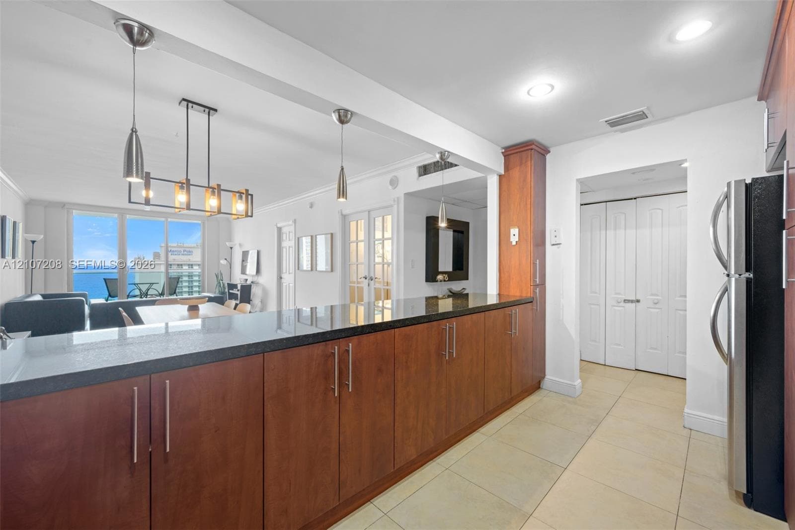 Kitchen featuring wood cabinetry, dark stone-finish countertops, recessed lighting, tile flooring, and a multi-light pendant fixture