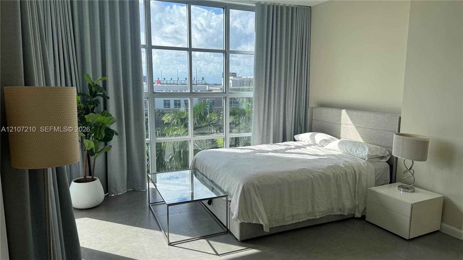 Floor-to-ceiling windows featuring a grid pane design, expansive natural lighting, and neutral-toned tile flooring