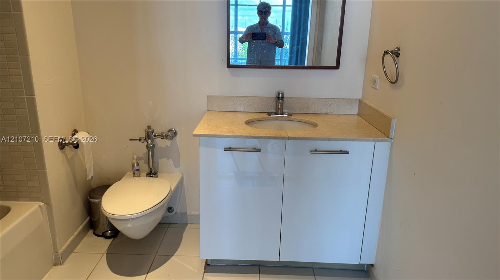 Vanity featuring a stone-surface countertop, under-mount sink, white cabinetry with metal hardware, and wall-mounted mirror