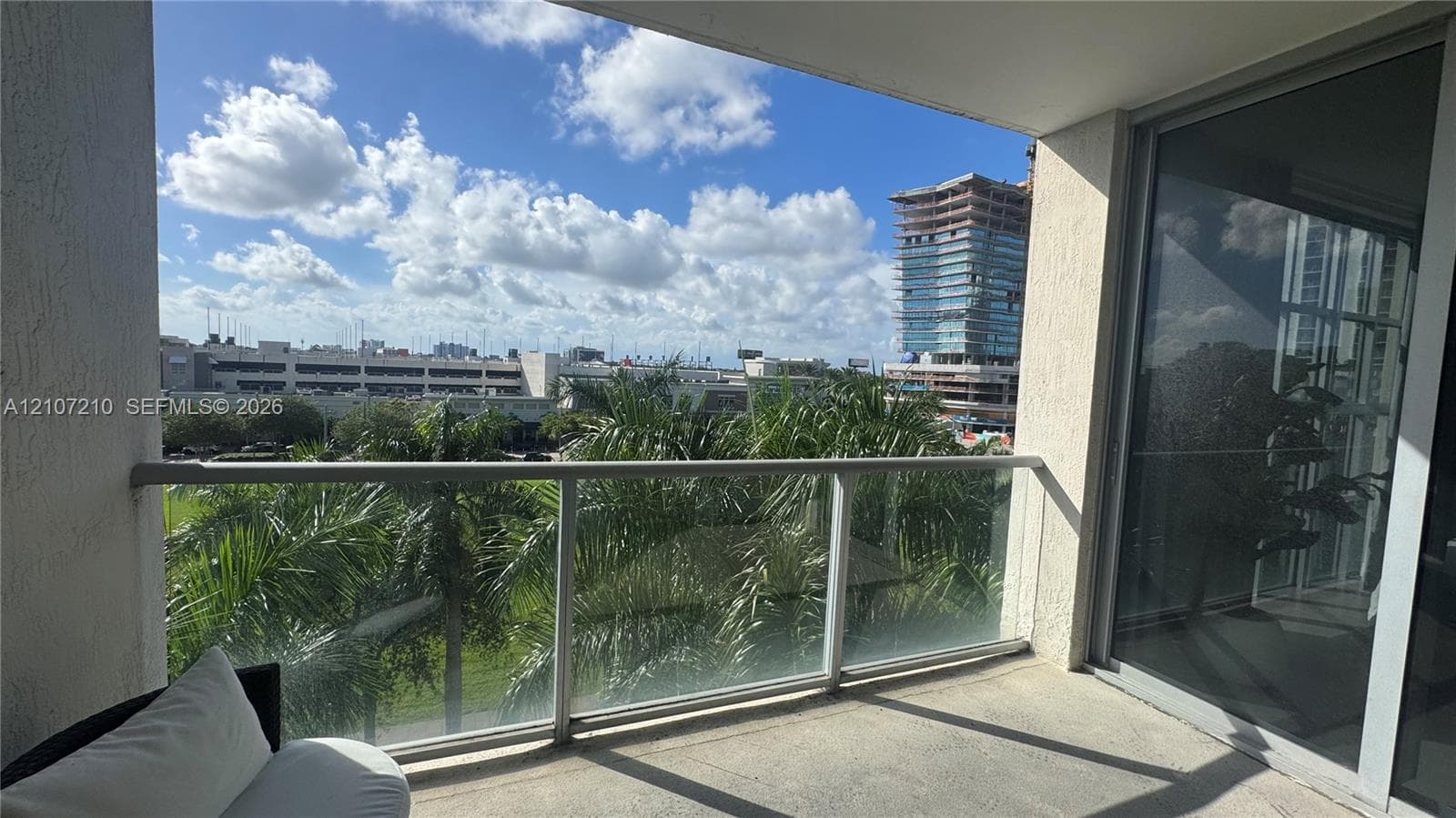 Covered balcony featuring concrete flooring, a glass and metal railing, and large sliding glass door entry
