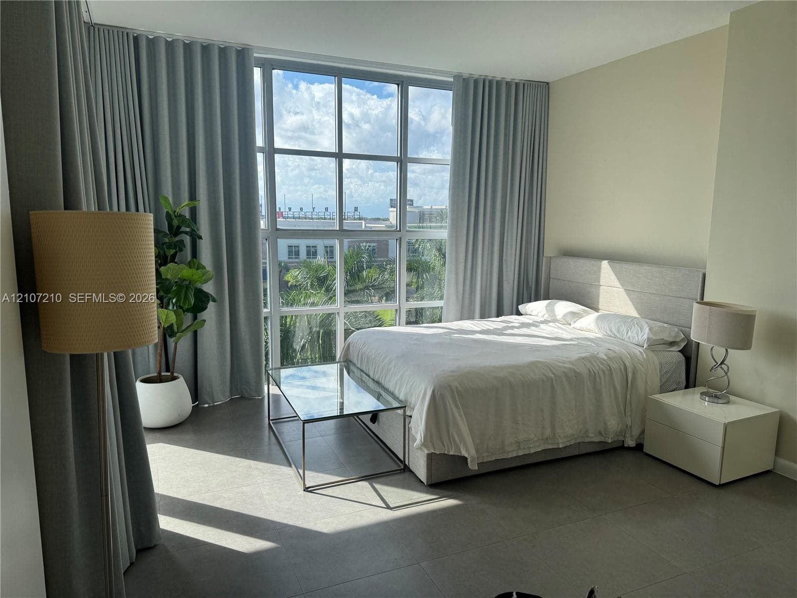 Floor-to-ceiling grid windows with neutral floor-to-ceiling drapery and large-format tile flooring