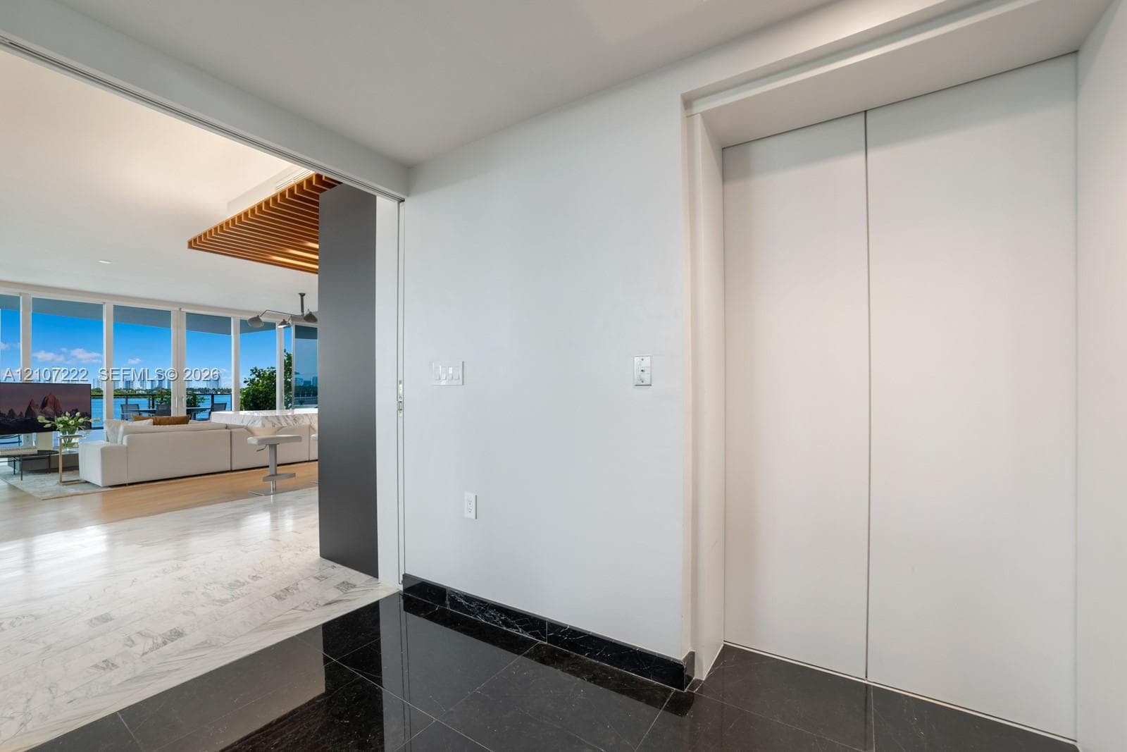 Entryway featuring polished black stone flooring, flush-mounted floor-to-ceiling cabinetry, and light-toned stone tile flooring