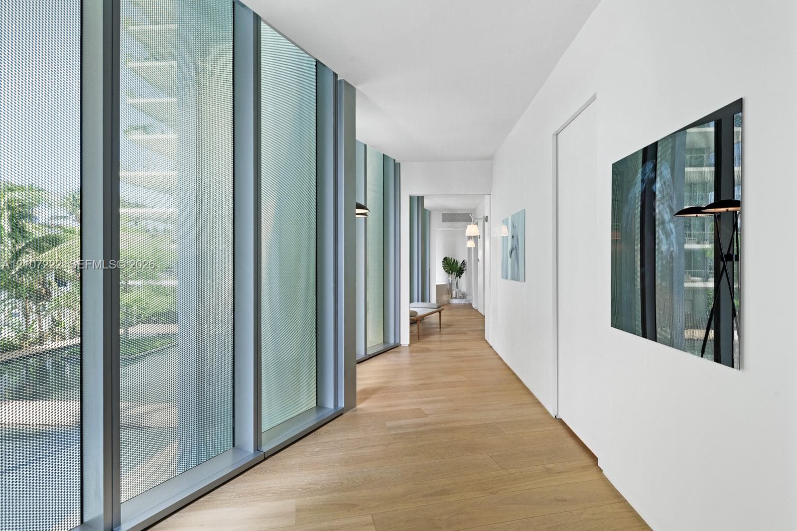 Floor-to-ceiling metal-framed windows, wood-finish flooring, and crisp white walls