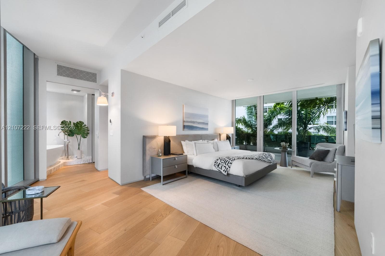 Floor-to-ceiling glass windows, wide-plank wood-finish flooring, recessed lighting, and a freestanding soaking tub