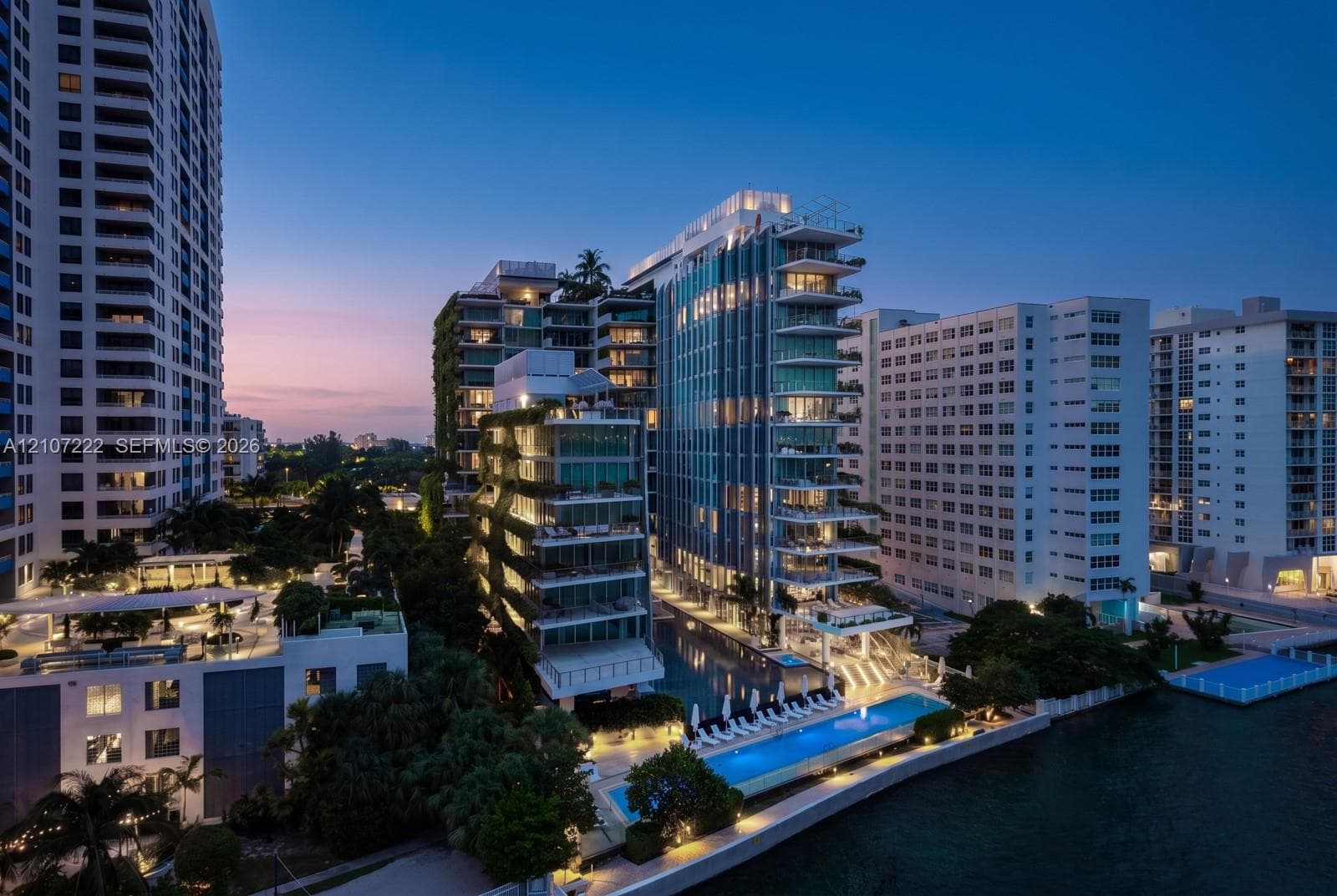 High-rise residential exterior featuring expansive glass balconies, vertical garden facades, waterfront lap pool, and integrated hardscaping