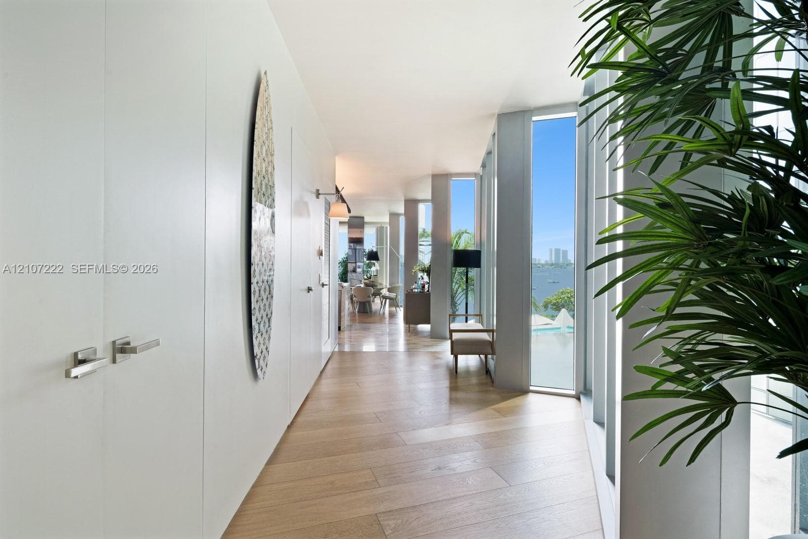 Hallway featuring wood-finish flooring, floor-to-ceiling windows, and flush-mounted cabinetry