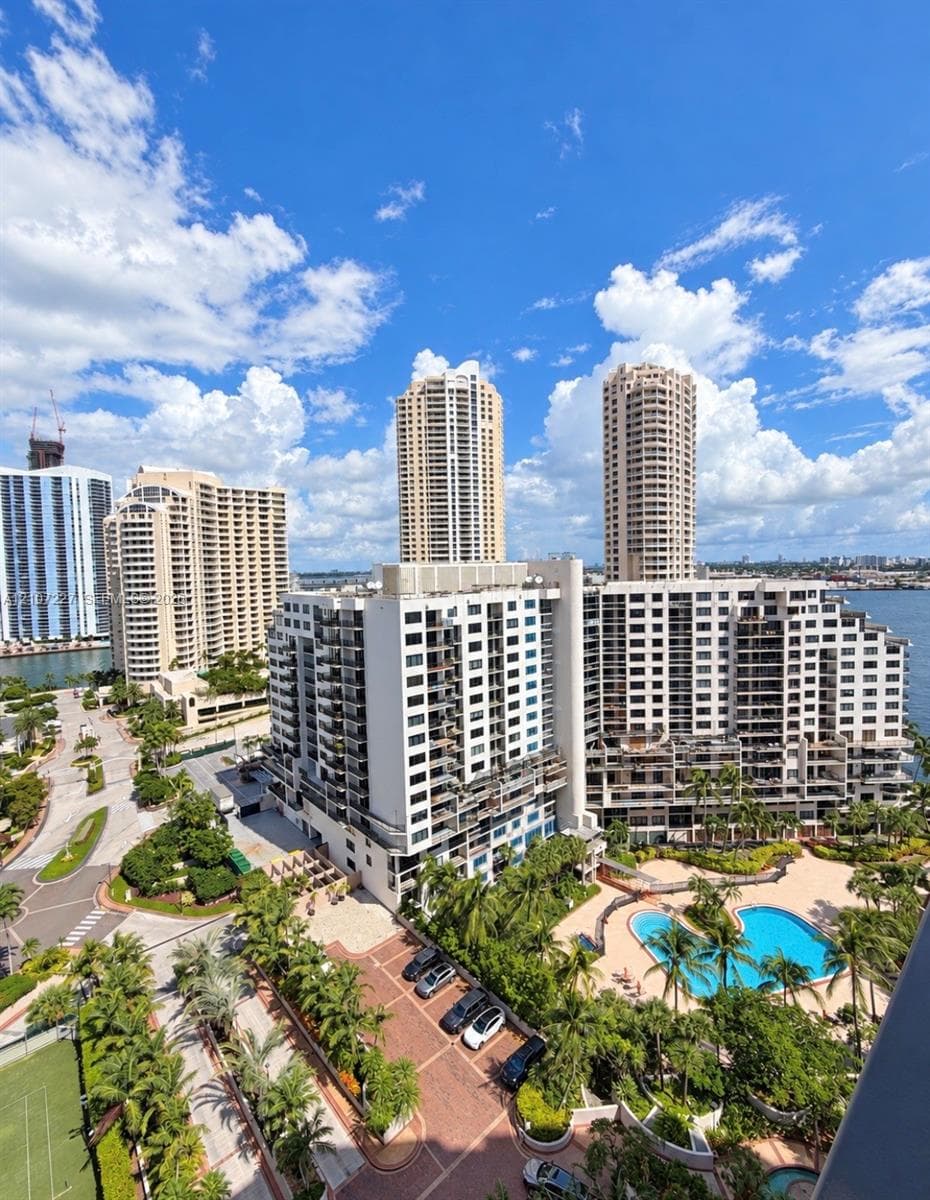 High-rise residential complex featuring a swimming pool, paved motor court, tennis court, and landscaping