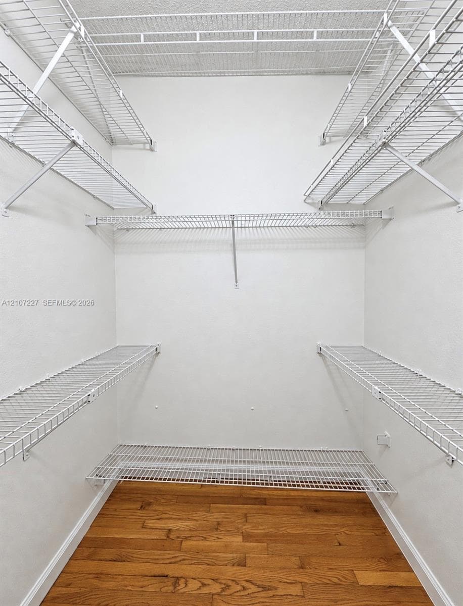 Storage space featuring white wire shelving across multiple tiers and wood-finish flooring