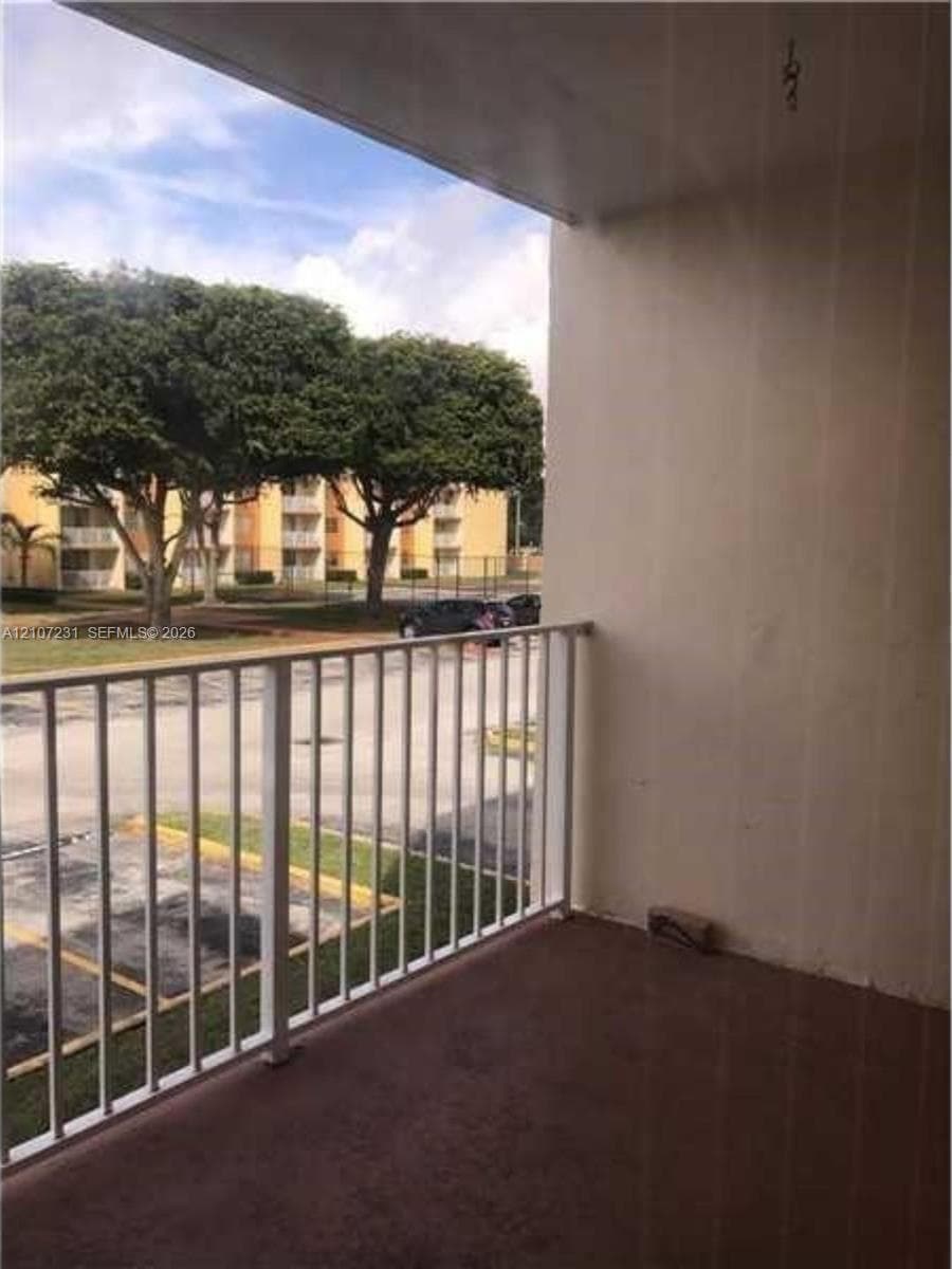 Covered balcony featuring white metal railings and concrete flooring