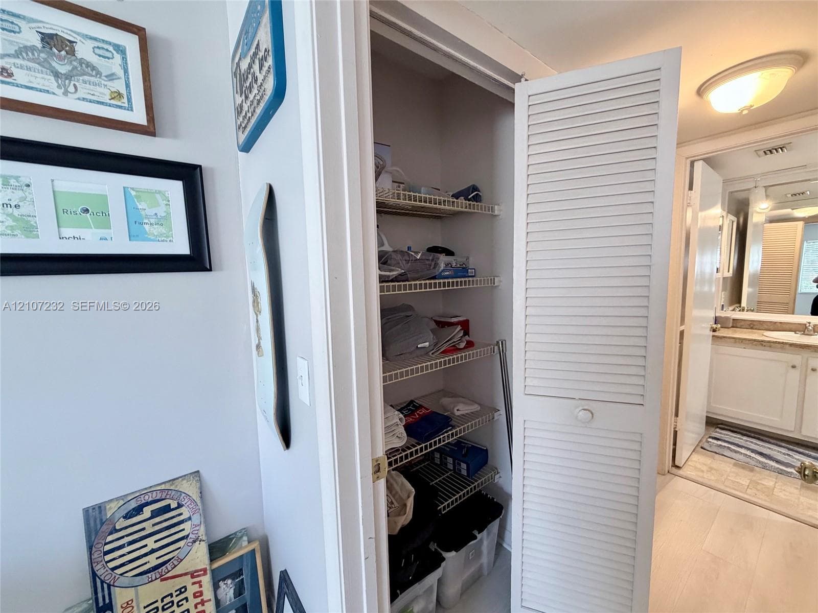 Storage closet featuring white louvered doors and multi-tier wire shelving