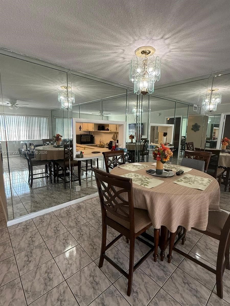 Full-wall mirrored accent, decorative multi-tiered light fixture, and ceramic tile flooring