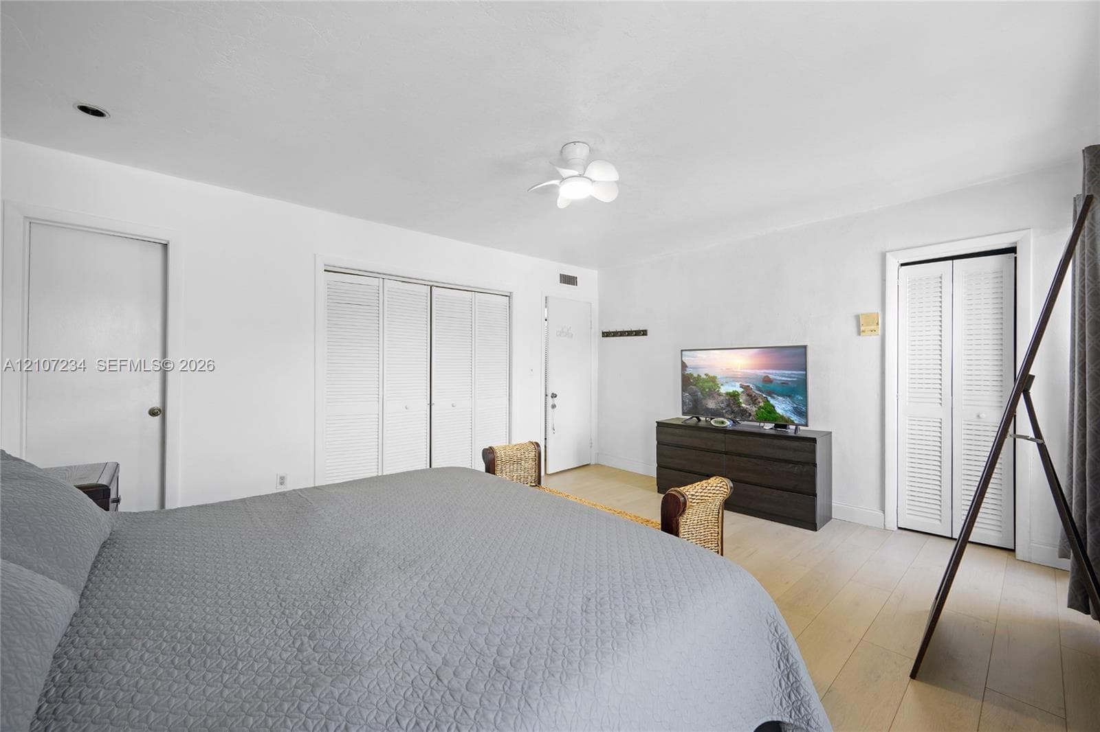 Light-toned wood-finish flooring, recessed ceiling lighting, a multi-light flush mount fixture, and double-door closets with louvered panels
