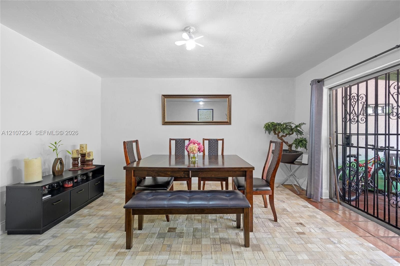 Interior space featuring a textured tile floor, sliding glass door with a decorative metal security screen, and a flush-mount ceiling light fixture
