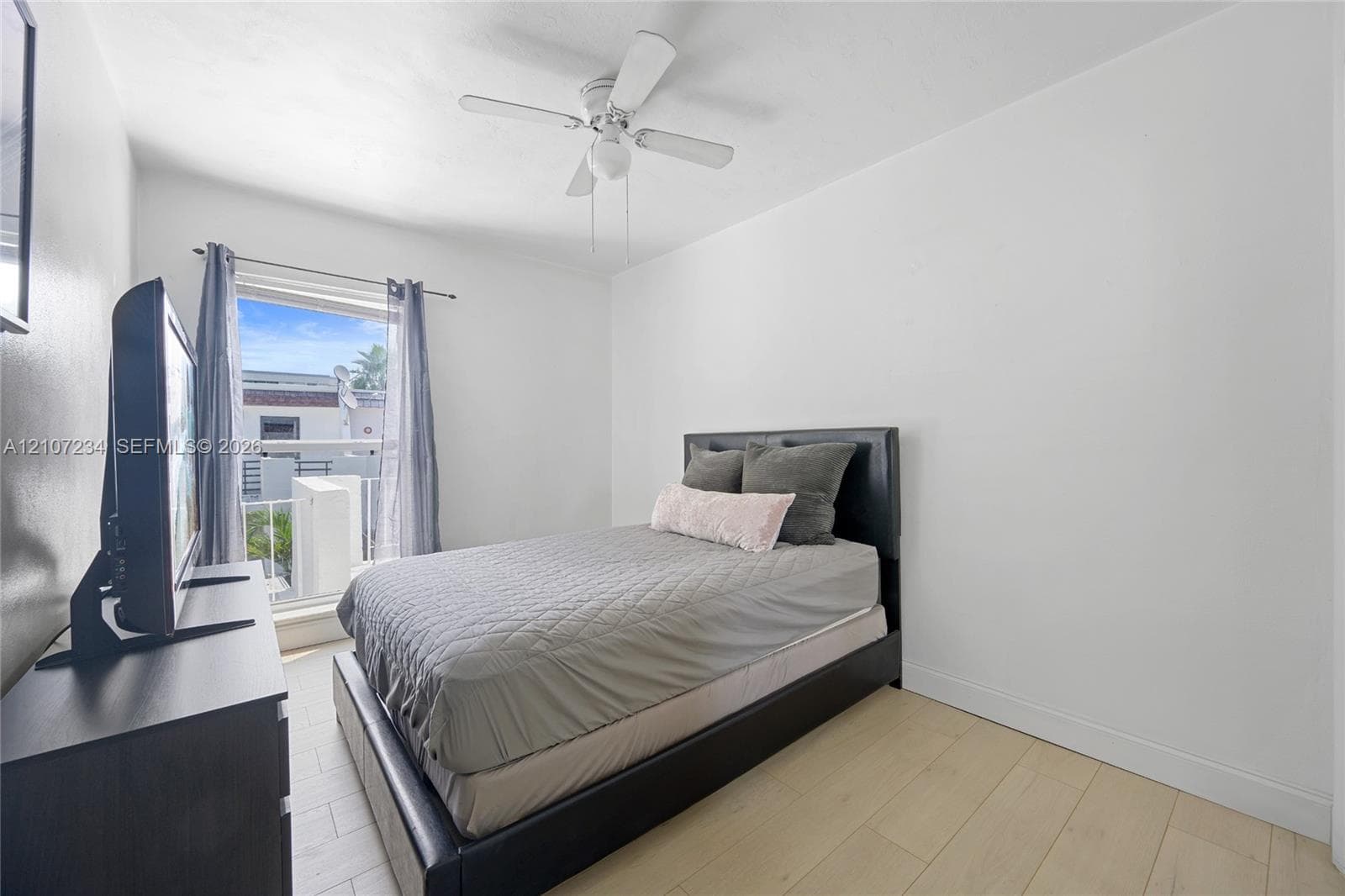 Neutral-toned wood-finish flooring, white wall finishes, and a four-blade ceiling fan with integrated lighting