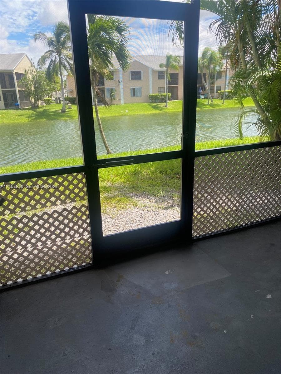 Screened-in patio with dark metal framing, white lattice accents, and concrete flooring
