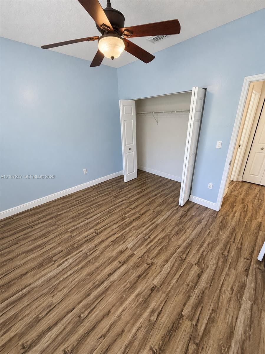 Room featuring wood-finish flooring, a ceiling fan with integrated light, and a closet with bifold doors
