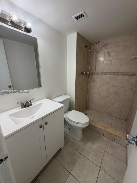 White vanity with a rectangular sink, wall-mounted three-light fixture, mirror, tile-surround shower, and tile flooring