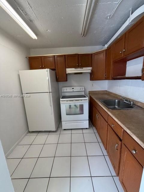 Kitchen featuring wood cabinetry, solid surface countertops, stainless steel sink, white electric range, and tiled flooring