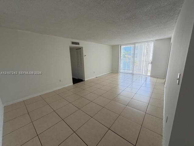 Spacious interior featuring neutral ceramic tile flooring, sliding glass doors, and a textured ceiling finish
