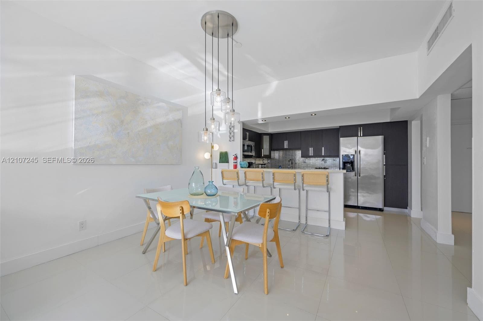 Kitchen featuring dark cabinetry, stainless steel appliances, breakfast bar, and multi-light pendant fixture over tile flooring