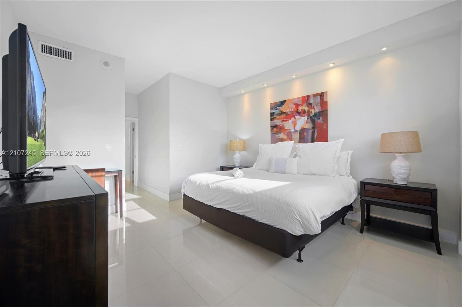 Neutral-toned room featuring large-format tile flooring, recessed ceiling lighting, and a recessed architectural wall niche above the bed area