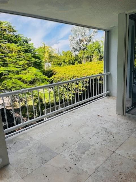 Covered balcony featuring large-format stone tiling and a white metal railing