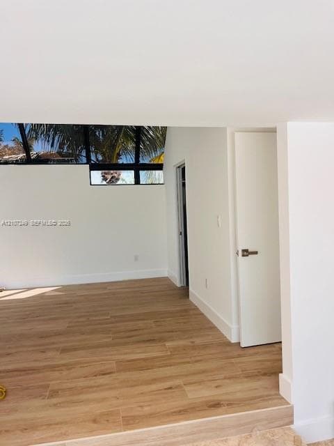 Sunroom featuring wood-finish flooring, vaulted ceilings, and extensive glass paneling with integrated black frames