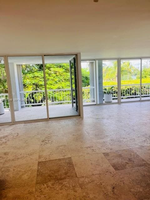 Large-format natural stone tile flooring, expansive glass sliding doors, and a wrap-around balcony featuring white metal railings