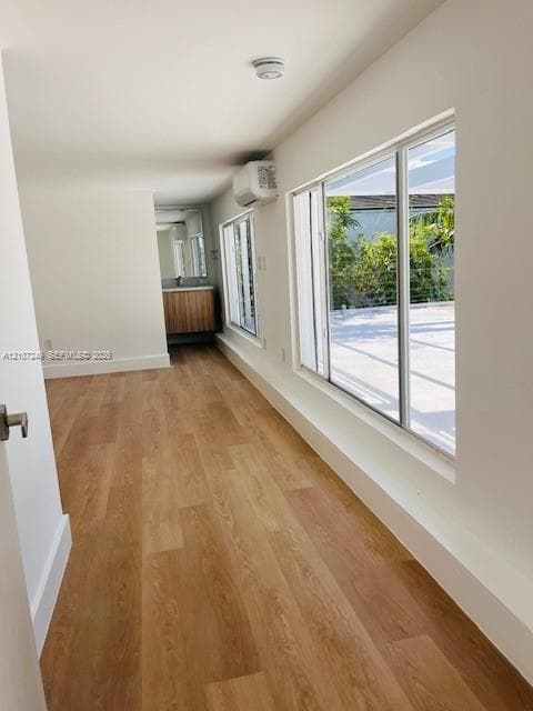 Wood-finish flooring, floor-to-ceiling windows, wall-mounted climate control unit, and a vanity featuring a wood-finish cabinet