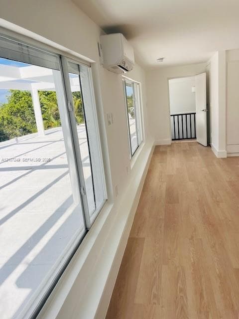 Interior featuring wood-finish flooring, large sliding glass doors, a wall-mounted ductless air conditioning unit, and minimalist white wall finishes